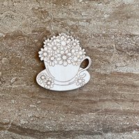 Handmade wooden DIY cutout of a coffee cup filled with flowers that are ready for paint or decorations