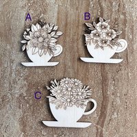 Handmade wooden DIY cutout of a coffee cup filled with flowers that are ready for paint or decorations
