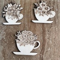 Handmade wooden DIY cutout of a coffee cup filled with flowers that are ready for paint or decorations