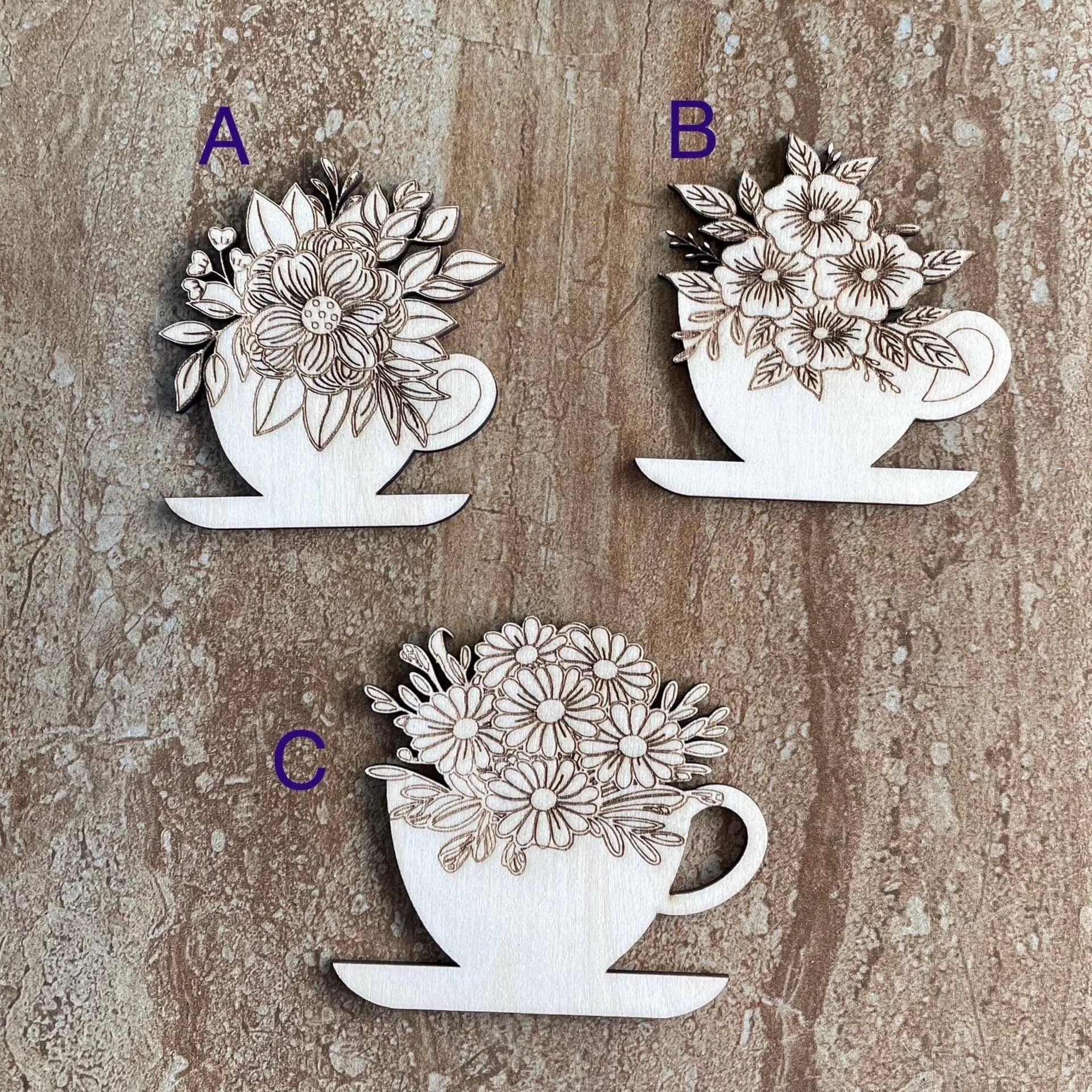 Handmade wooden DIY cutout of a coffee cup filled with flowers that are ready for paint or decorations