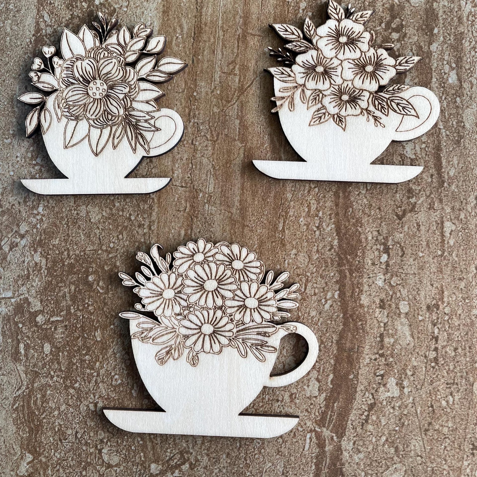 Handmade wooden DIY cutout of a coffee cup filled with flowers that are ready for paint or decorations